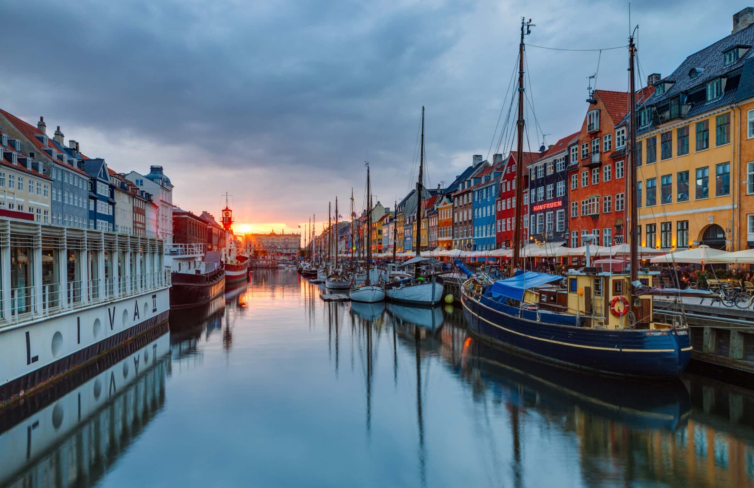 Nyhavn's coloured townhouses and moored wooden boats reflected in still water at sunset