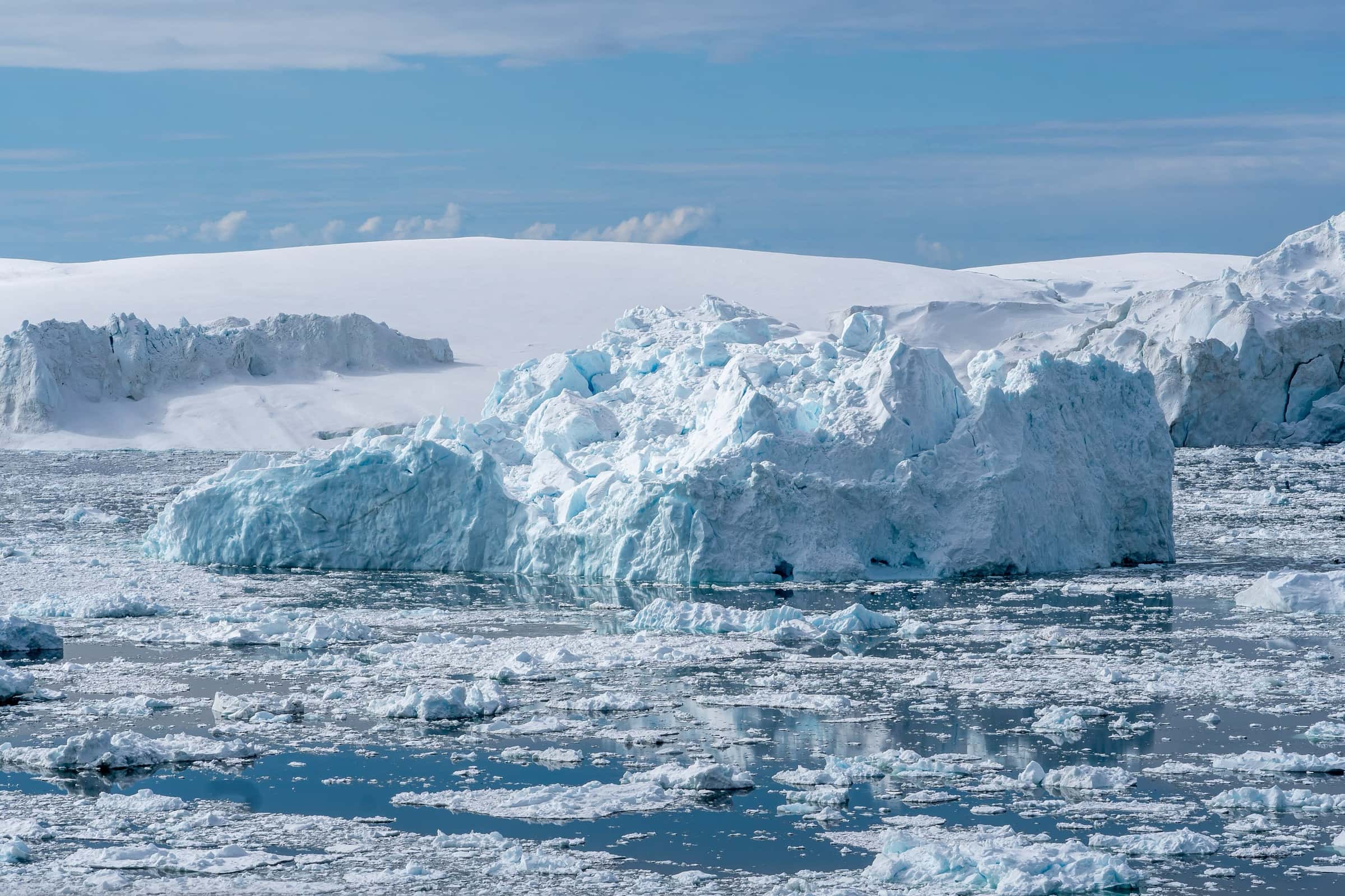 A vast blue-white iceberg wall rising from dark water at Ilulissat Kangerlua