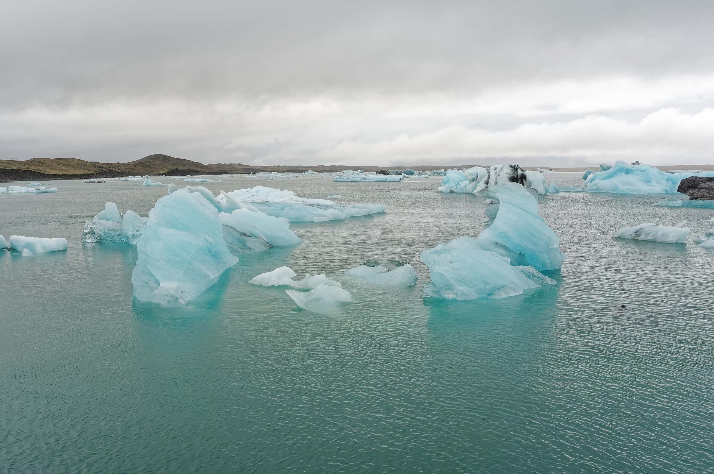 Blue icebergs drifting on the still water of Jökulsárlón glacier lagoon