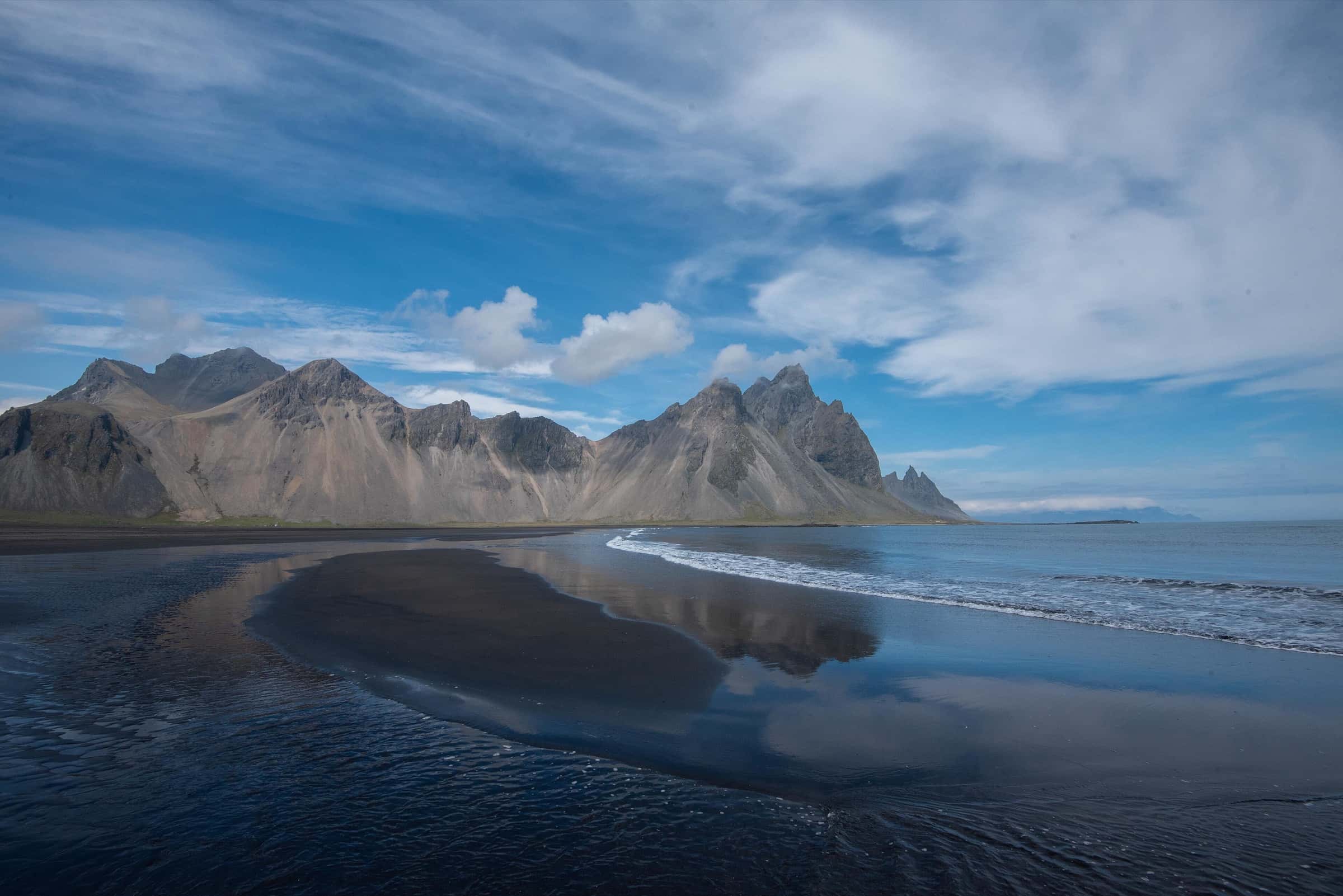Vestrahorn's ridgeline reflected on the wet black-sand beach at Stokksnes