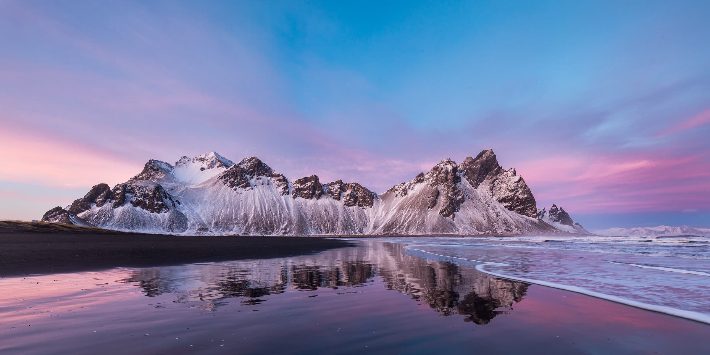 Vestrahorn mountain at sunset under a pink sky, mirrored in the tidal lagoon at Stokksnes