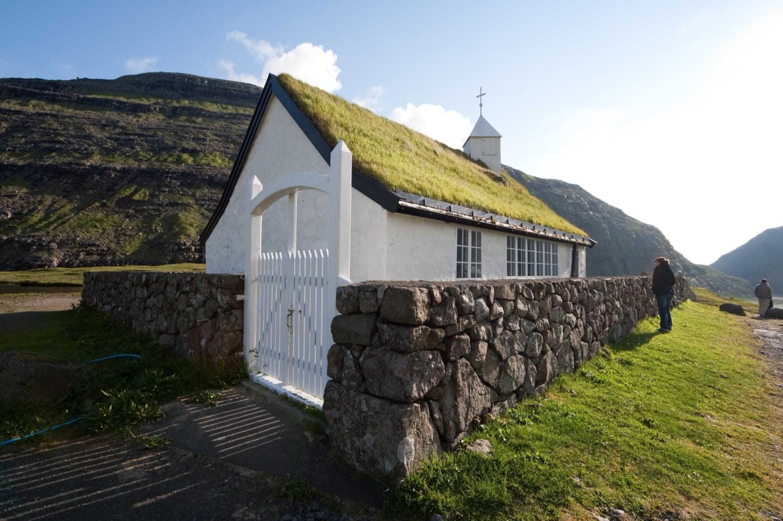 The turf-roofed church at Saksun behind a dry-stone wall, with a lone visitor at the gate