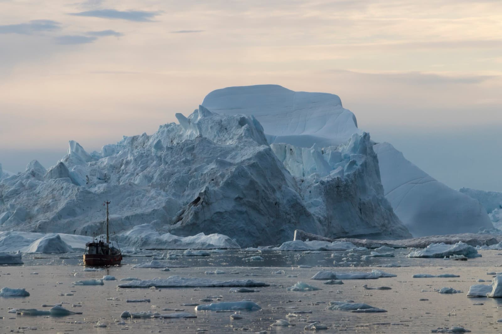 A small boat dwarfed by an enormous iceberg in Disko Bay