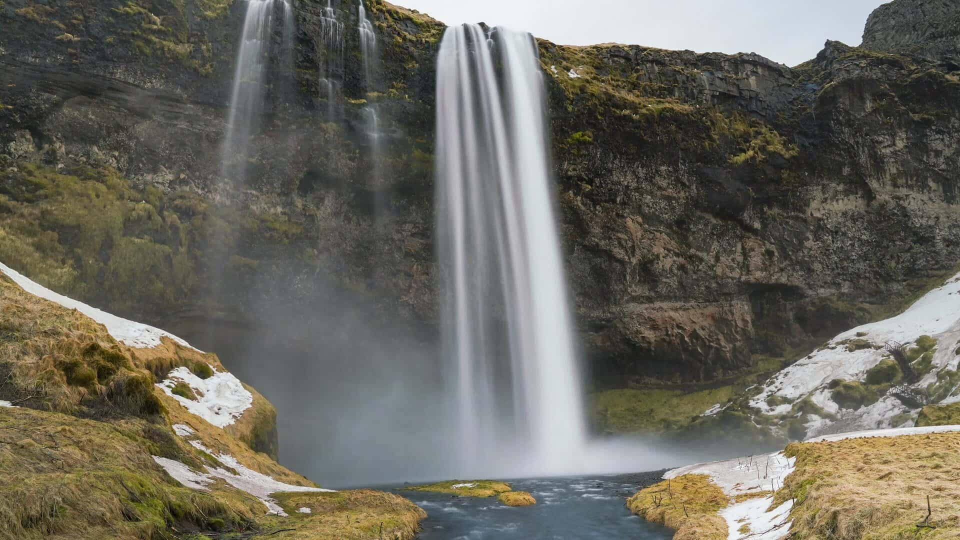 Seljalandsfoss waterfall pouring over mossy cliffs in daylight, south Iceland